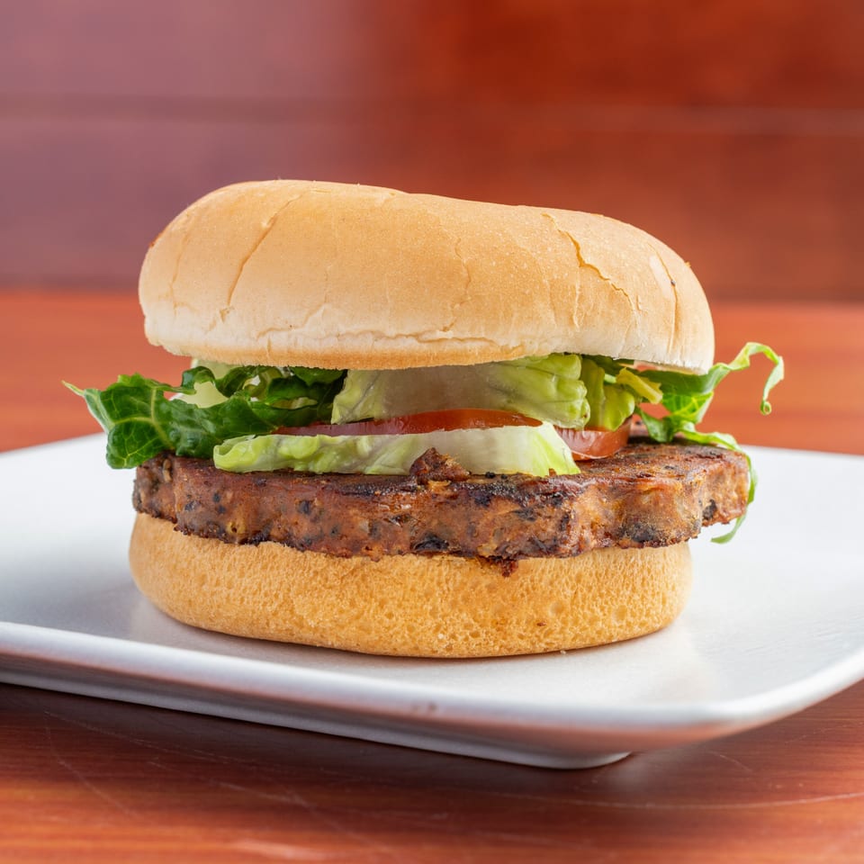Morehead Burger Company's burger with a thick patty, lettuce, and tomato on a white bun.