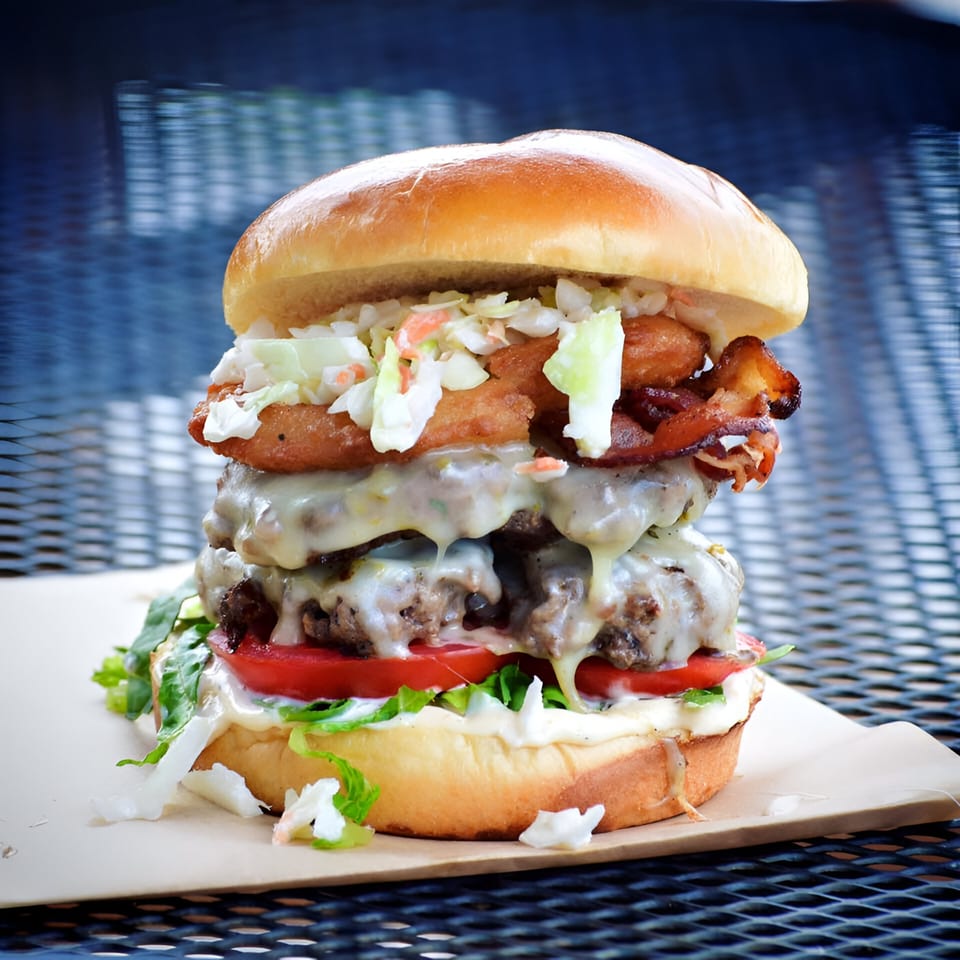 A towering Morehead Burger with double patties, cheese, bacon, onion rings, and coleslaw.