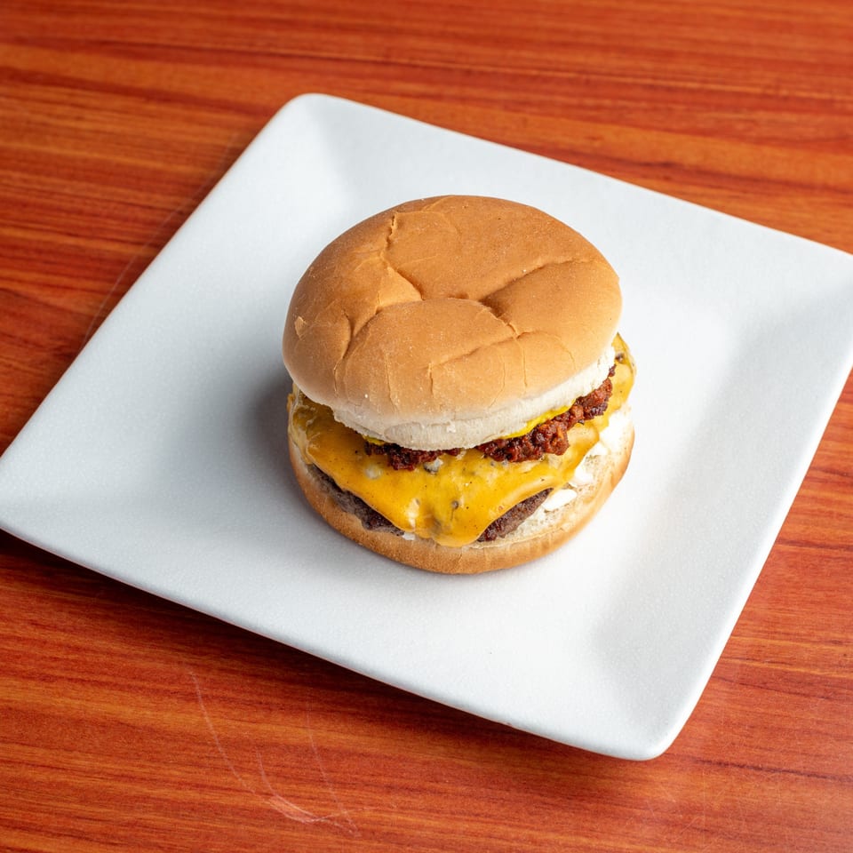 Morehead Burger Company's bacon cheeseburger with melted cheese and crispy bacon bits on a white plate.